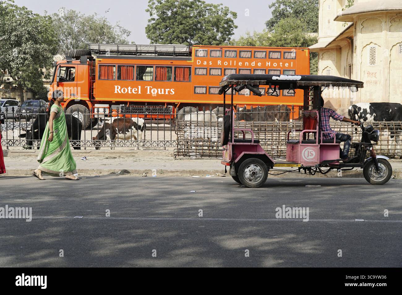 Jaipur, Rajasthan, India, Asia, scena di strada con una donna, un autobus turistico arancione e un tre ruote Foto Stock
