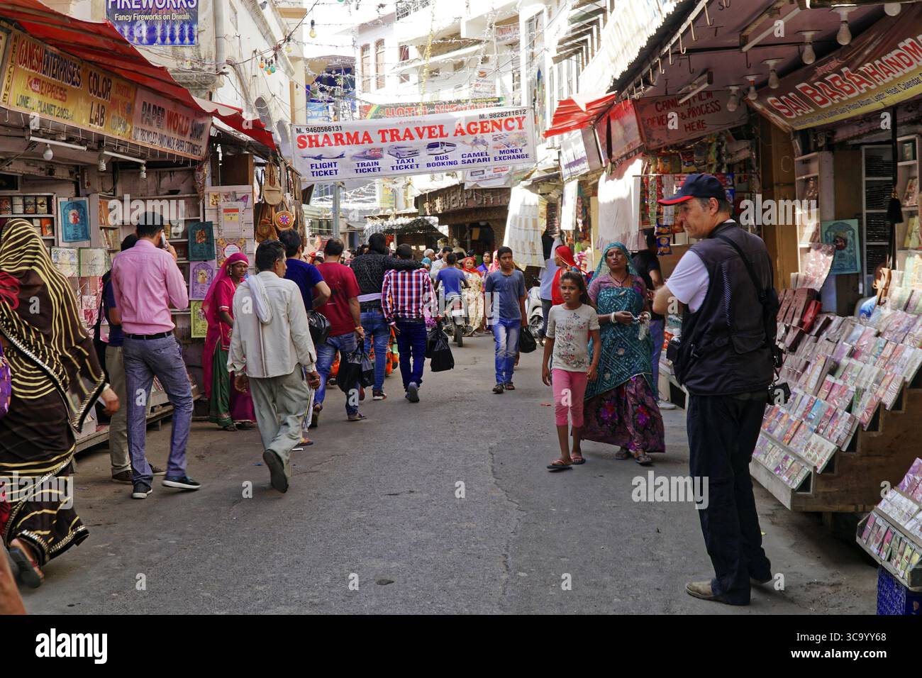 Jaipur, Rajasthan, India settentrionale, India, Asia, vivace strada indiana piena di gente, cartelli per agenzie di viaggio e bancarelle Foto Stock