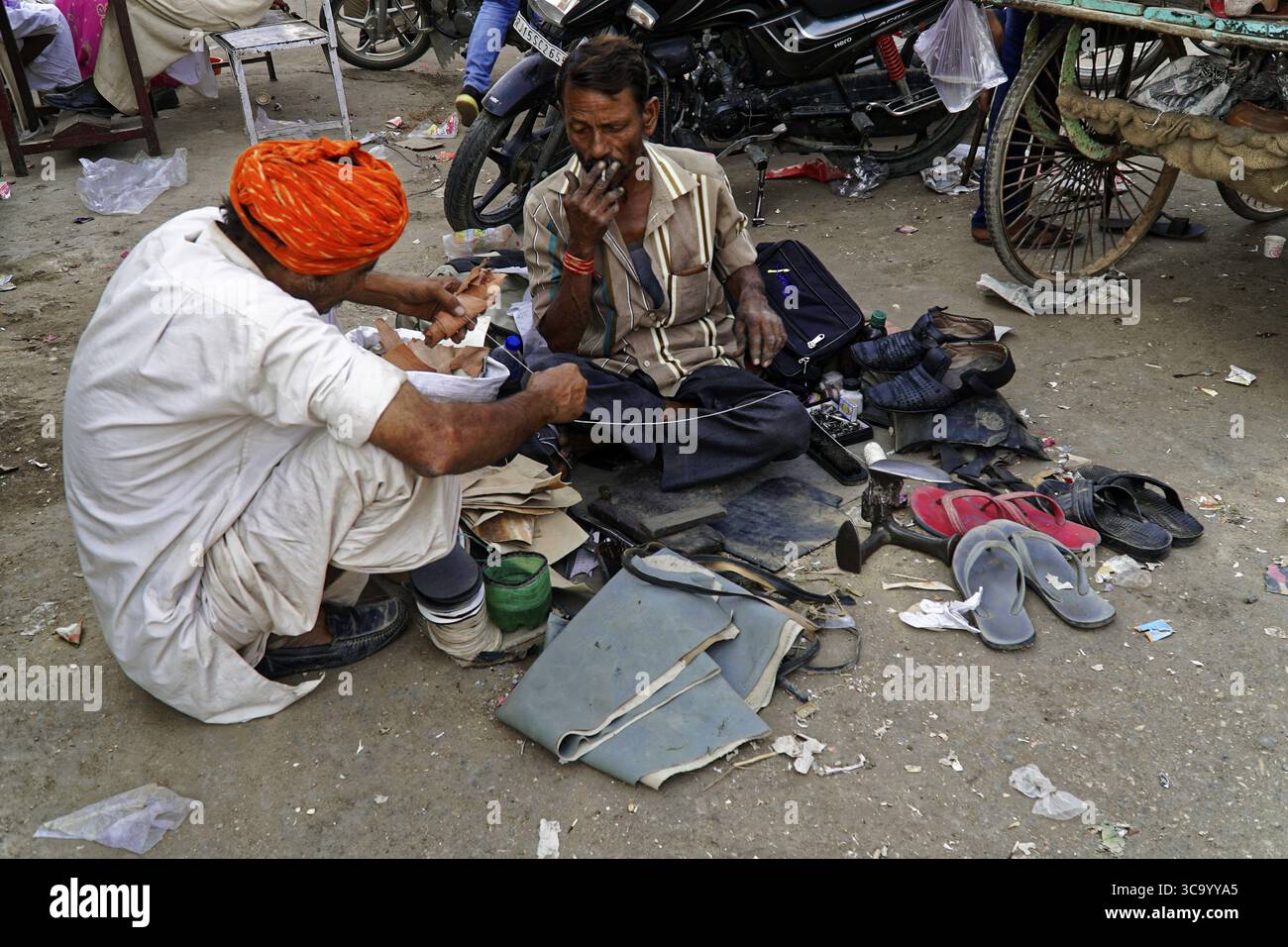 Due uomini seduti su una strada e che riparano scarpe, Jaisalmer, Kuri Desert, Rajasthan, India del Nord, India Foto Stock