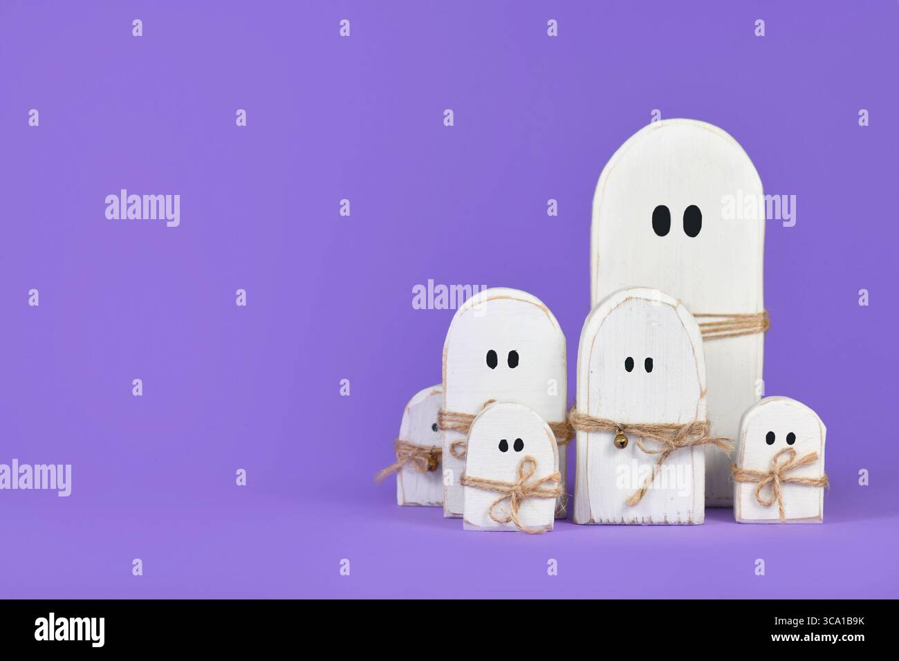 Graziosi ornamenti fantasma bianchi in legno per Halloween su sfondo viola Foto Stock