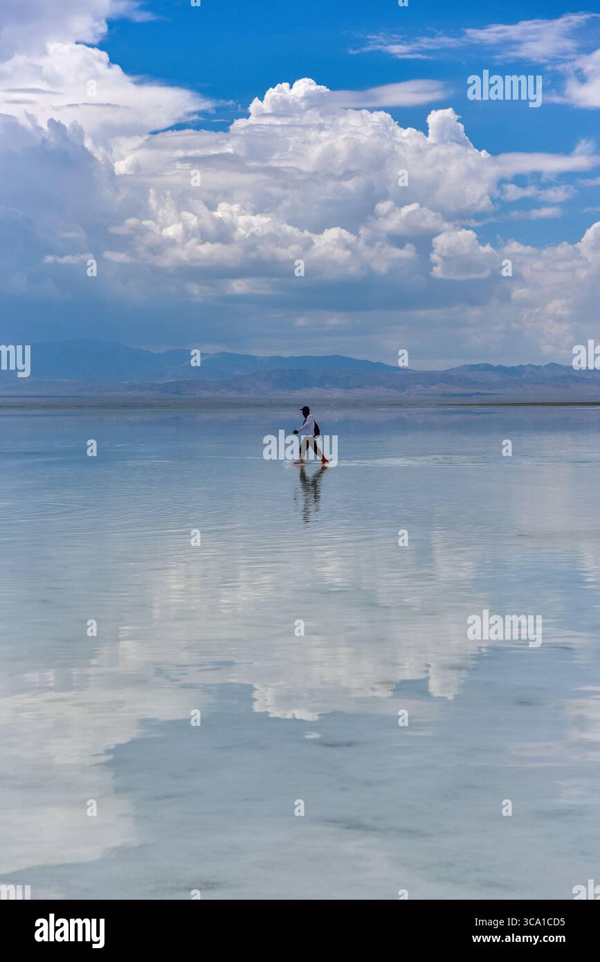 I turisti e le loro riflessioni sul lago salato di Chaka, noto anche come Sky Mirror nella contea di Ulan, prefettura di Haixi, provincia di Qinghai, Cina Foto Stock