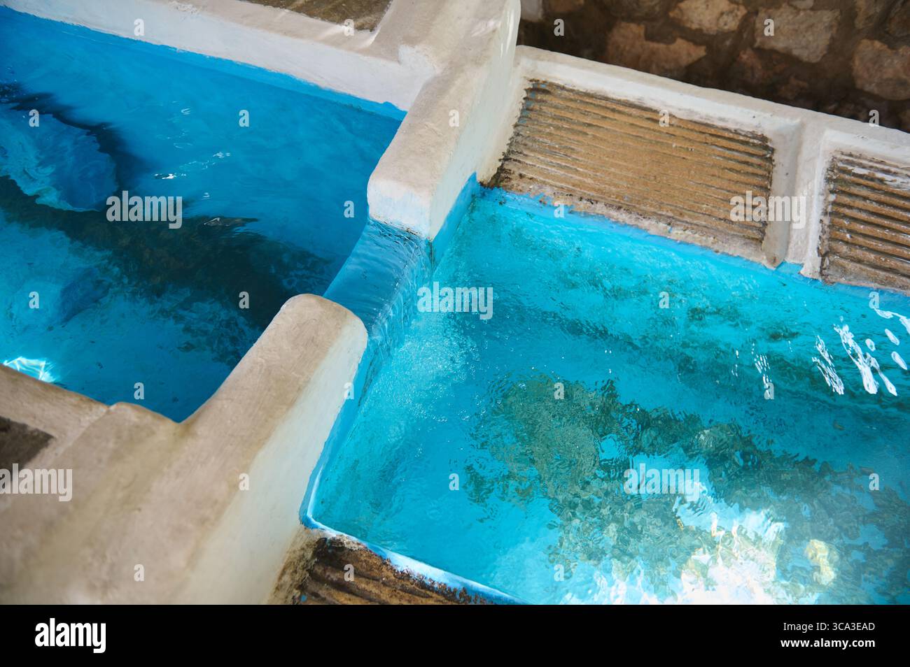 Un lavabo all'aperto in pietra pieno di acqua blu incontaminata che riflette la luce del sole. Simboleggia la semplicità, i metodi tradizionali e la b naturale Foto Stock