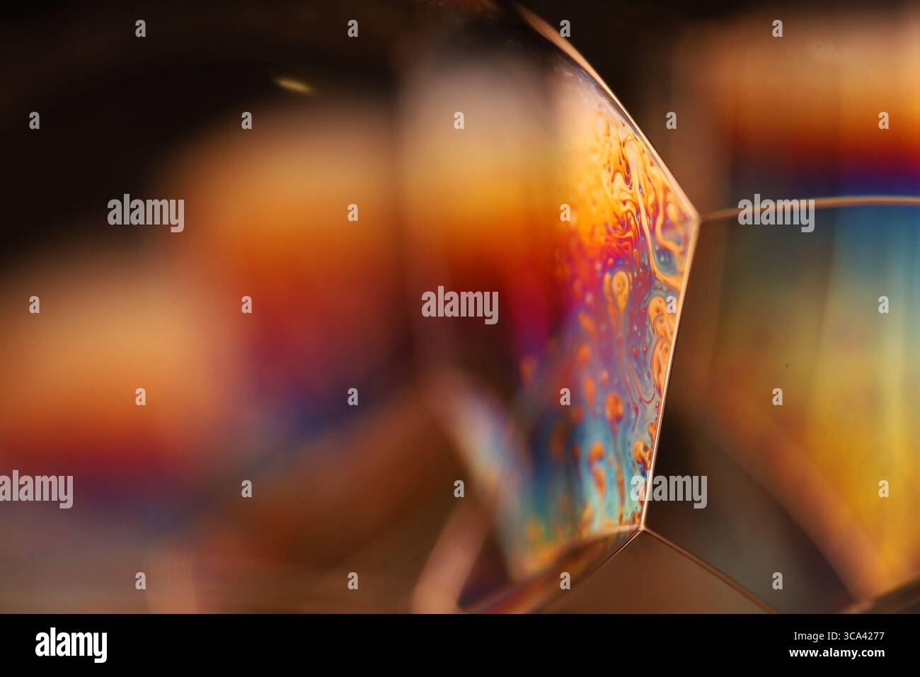 Macro di giunzioni di bolle di sapone dorate e arancioni con iridescenti motivi arcobaleno e movimento fluido geometrico Foto Stock