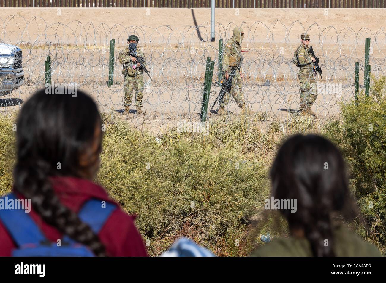 I bambini guardano mentre i soldati pattugliano il confine con il filo spinato vicino a Ciudad Juarez, un punto di riferimento per i problemi migratori. Foto Stock