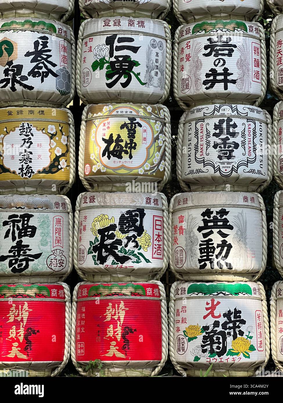 Botti di sake impilate adornate con calligrafia giapponese, un simbolo senza tempo di tradizione e celebrazione in Giappone. Foto Stock