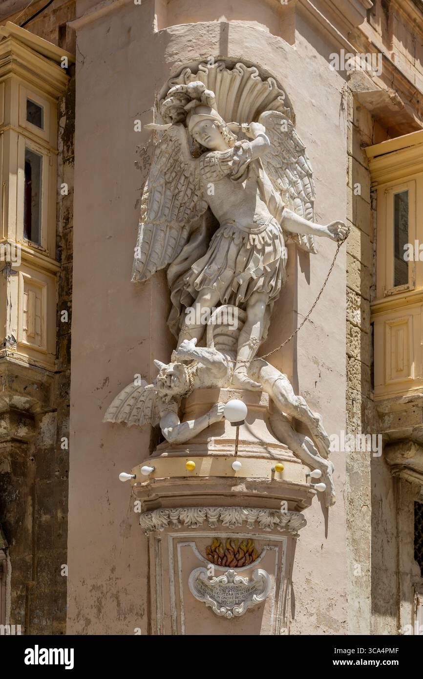 Statua di San Michele Arcangelo. Trovato all'incrocio tra St. Ursula Street e Archbishop Street. Sconfiggere il diavolo. La Valletta, Malta. Foto Stock