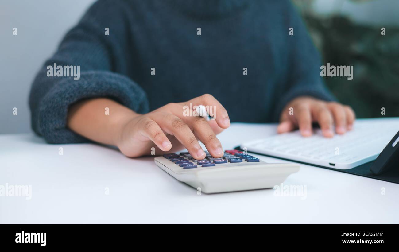 Persona che si occupa di attività finanziarie con calcolatrice e tablet digitale, simboleggiando contabilità, gestione del budget, preparazione fiscale e personale o piccolo Foto Stock