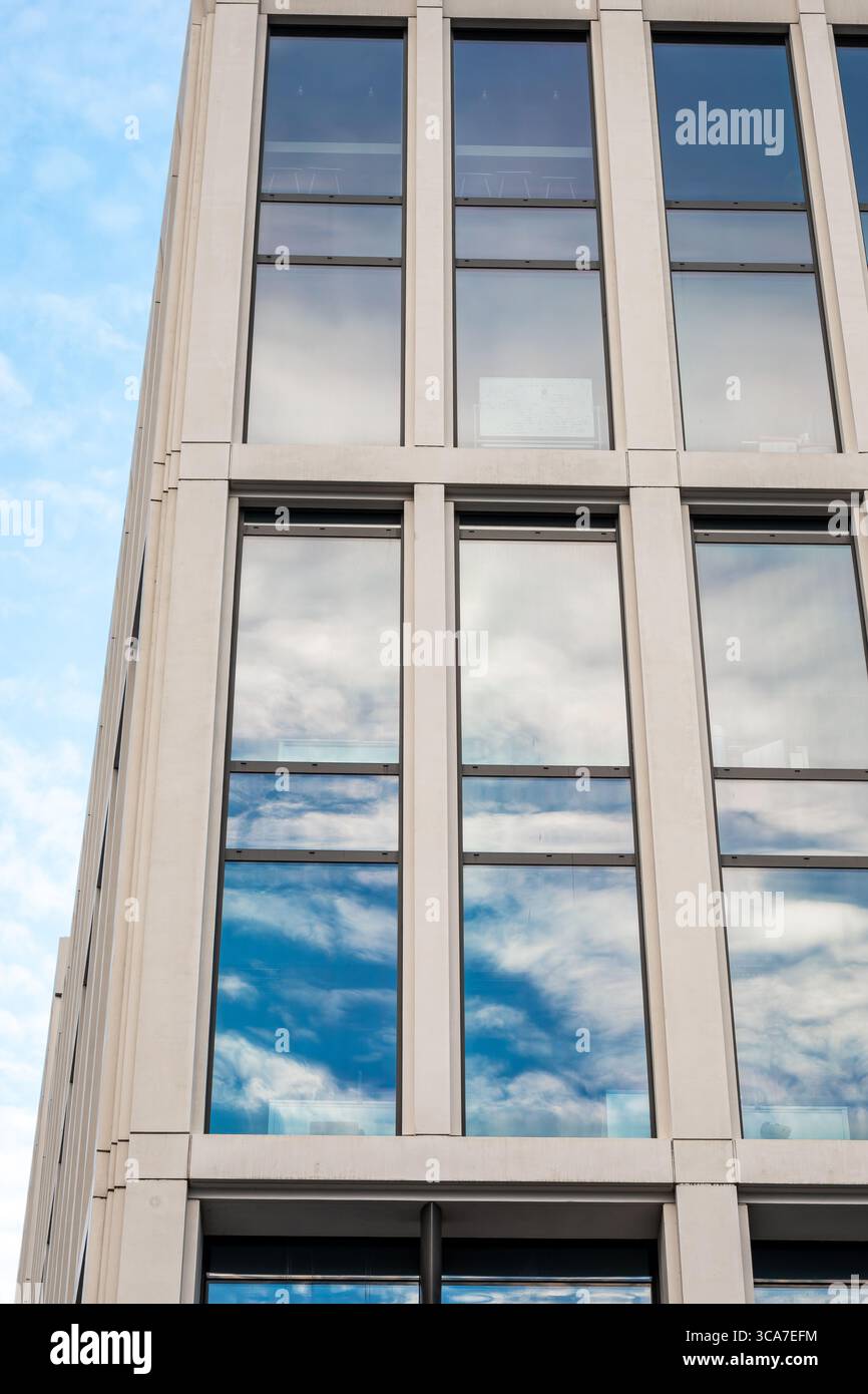 25 luglio 2025 Cork, Irlanda Un alto edificio con molte finestre che riflettono il cielo blu Foto Stock