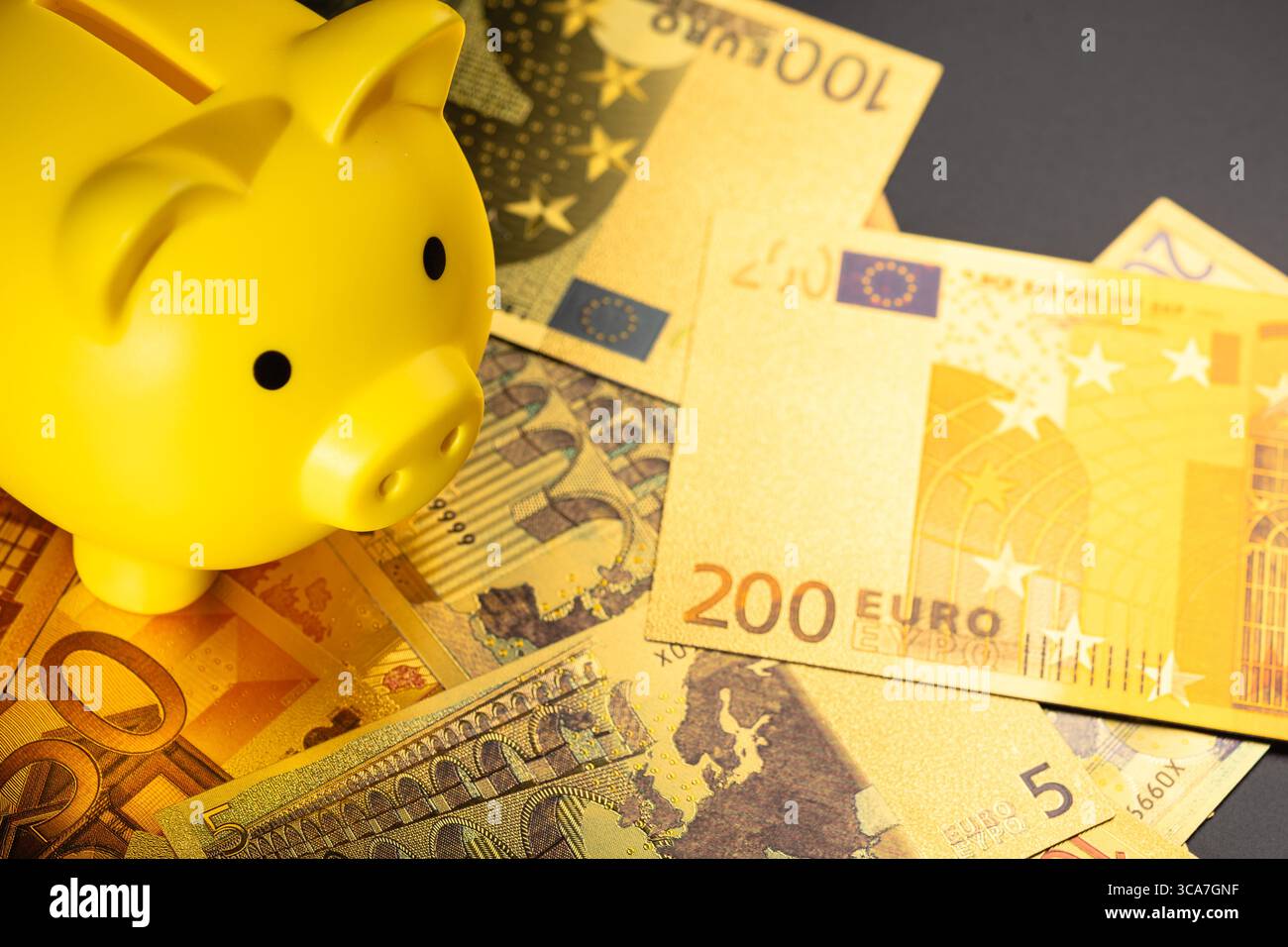 Il salvadanaio giallo siede sulle banconote in euro sparse, simboleggiando il risparmio finanziario e la stabilità economica. Ideale per temi legati al budget, al denaro Foto Stock