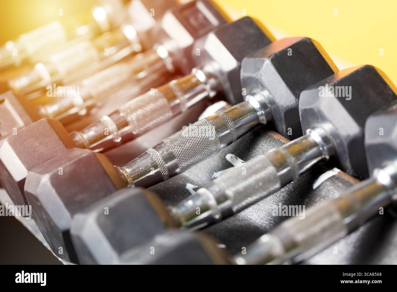Concetto di sport fitness. Set di manubri neri. Avvicinati a molti manubri in metallo sul rack nel centro fitness sportivo. Immagine a colori con messa a fuoco selettiva. Foto Stock
