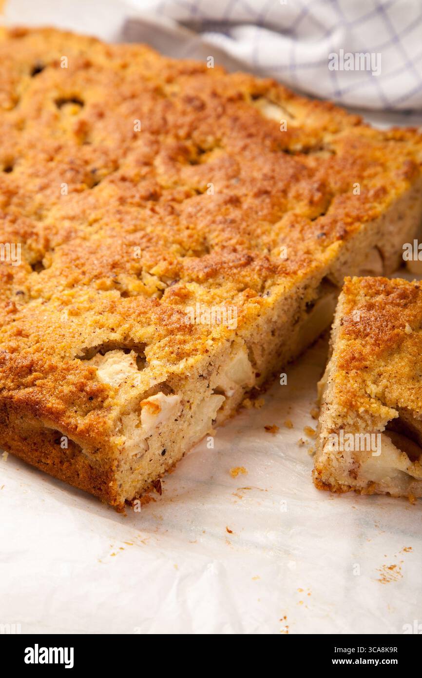 rustico e invitante primo piano di una torta alla cannella di mele appena sfornata, che mostra la sua crosta dorata e l'interno umido ripieno di teneri pezzi di mele Foto Stock
