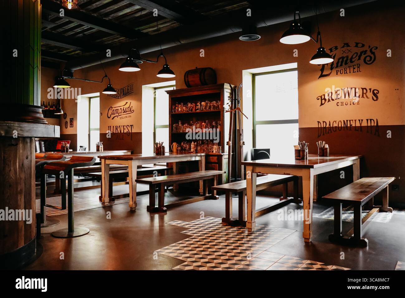 Autentico interno del pub. Illuminazione calda, atmosfera accogliente, scaffali da bar visibili con bottiglie sullo sfondo. Foto Stock