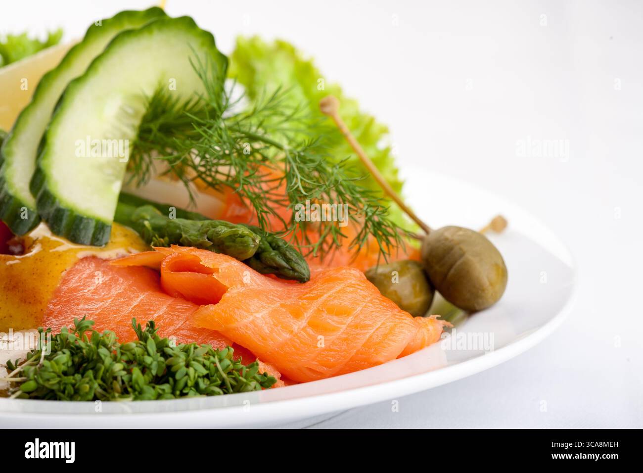 piatto salutare di salmone affumicato con cetriolo, pomodori, salsa ed erbe fresche su un piatto bianco, una foto da studio di un pasto gourmet Foto Stock