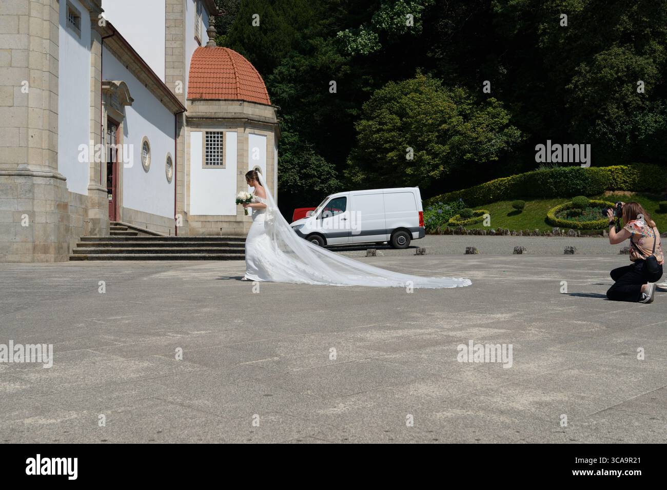 Sposa che cammina di fronte alla chiesa Bom Jesus do Monte a Braga, mentre un fotografo cattura il momento. Foto Stock