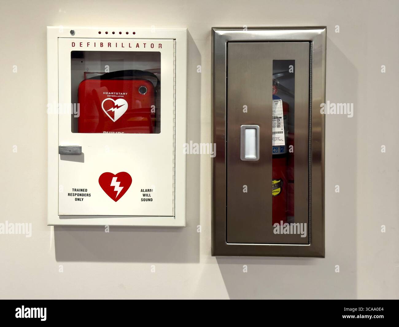 Defibrillatore montato a parete ed estintore Foto Stock