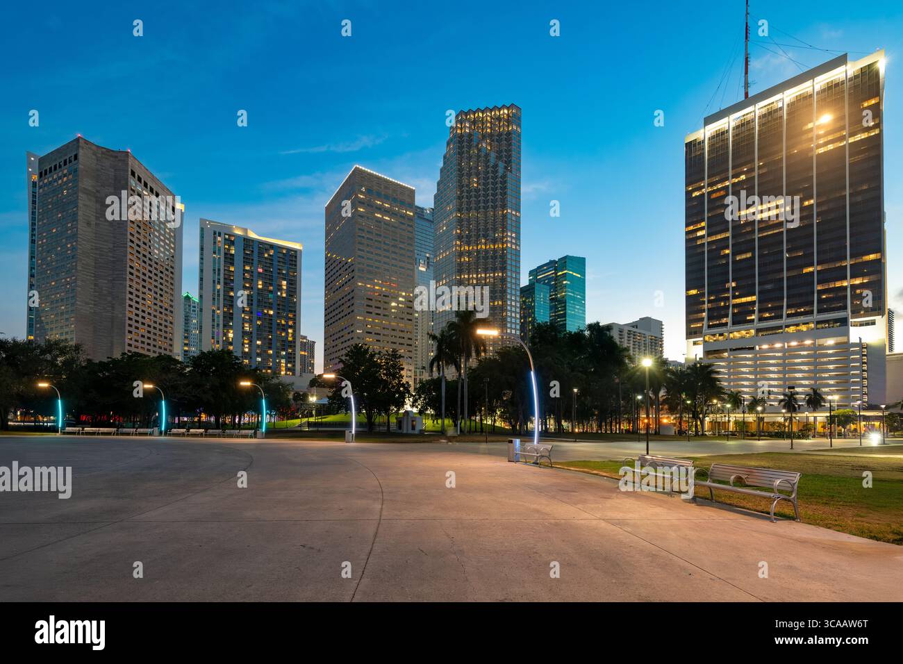 L'impressionante paesaggio urbano di Miami al crepuscolo, con edifici illuminati e un tranquillo Bayfront Park in primo piano. Foto Stock