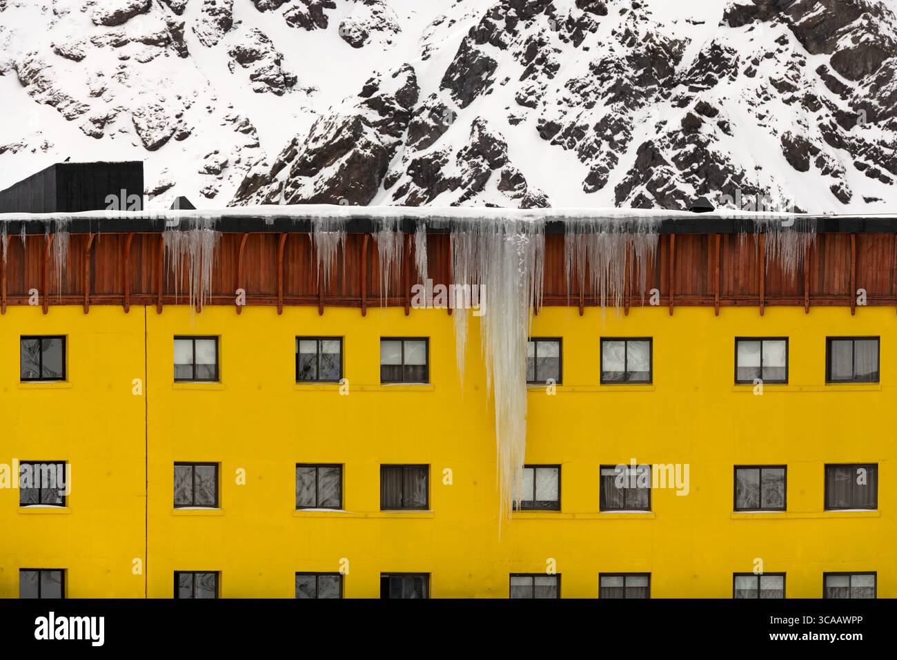 Portillo, Cile: Un primo piano della facciata dell'Hotel Portillo in Cile, con una suggestiva parete gialla che contrasta con la montagna innevata. Foto Stock