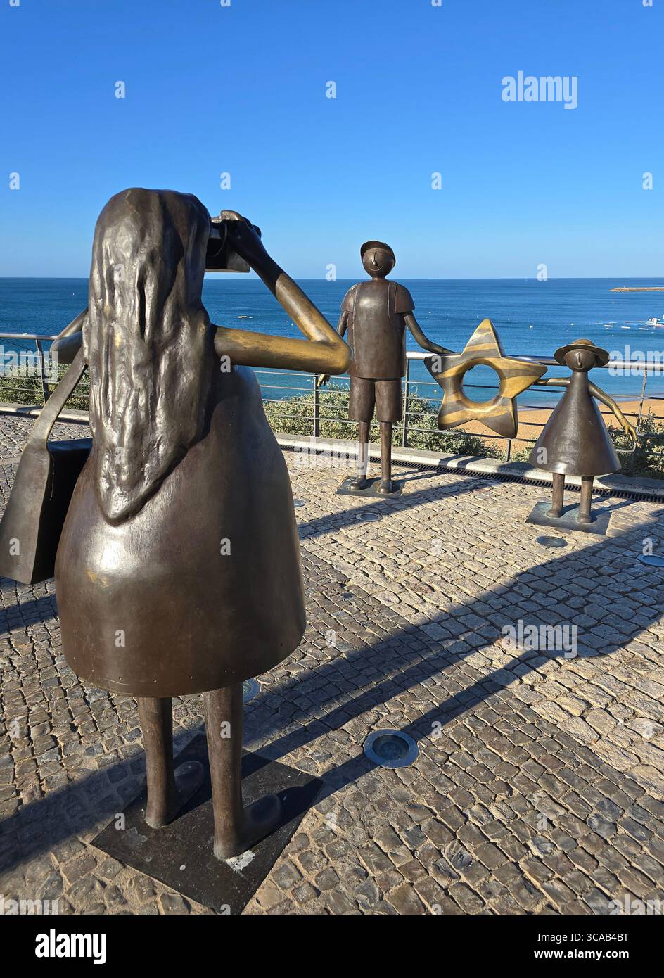 Scultura in bronzo di figure di famiglia sul lungomare di Albufeira, Algarve, Portogallo, con l'Oceano Atlantico nel backgroun - Immagine stock catturata con smartphone