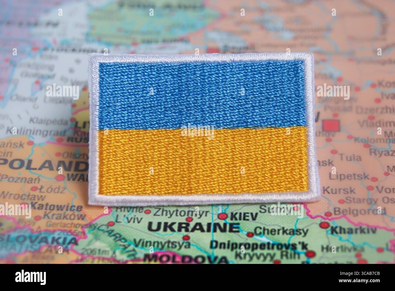 Bandiera Ucraina ricamata su una mappa mondiale sull'Ucraina, simboleggiando l'orgoglio nazionale, l'ispirazione per i viaggi e il turismo ecosostenibile. Foto Stock