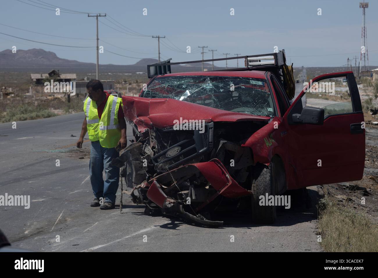 In mezzo alla crescente violenza urbana a Ciudad Juarez, un uomo ispeziona un camion rosso danneggiato, una probabile vittima di recenti conflitti. Foto Stock