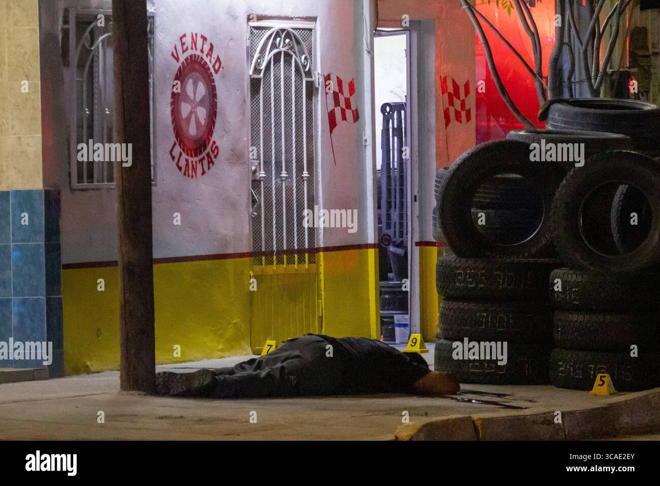 Una vittima di violenza urbana si trova accanto alle gomme a Ciudad Juarez. Foto Stock