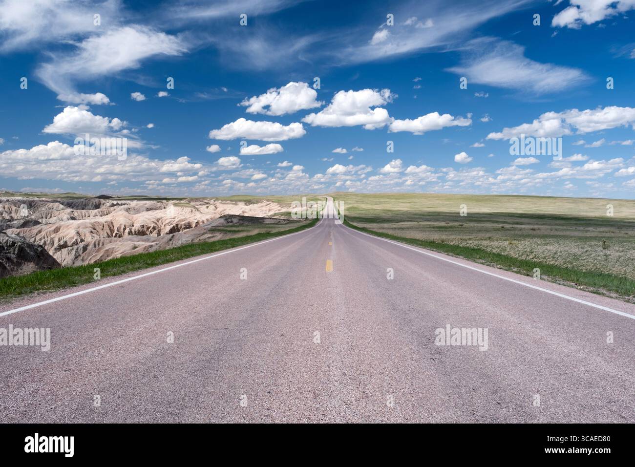 Prospettiva forzata guardando all'orizzonte lungo un'autostrada rurale sulle pianure del Badlands National Park nel South Dakota Foto Stock