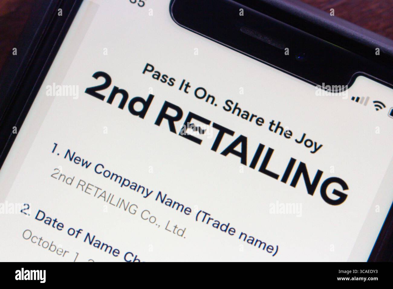 Display dello smartphone con annuncio del cambio del nome dell'azienda al secondo DETTAGLIO, con marchio moderno e slogan aziendale. Foto Stock