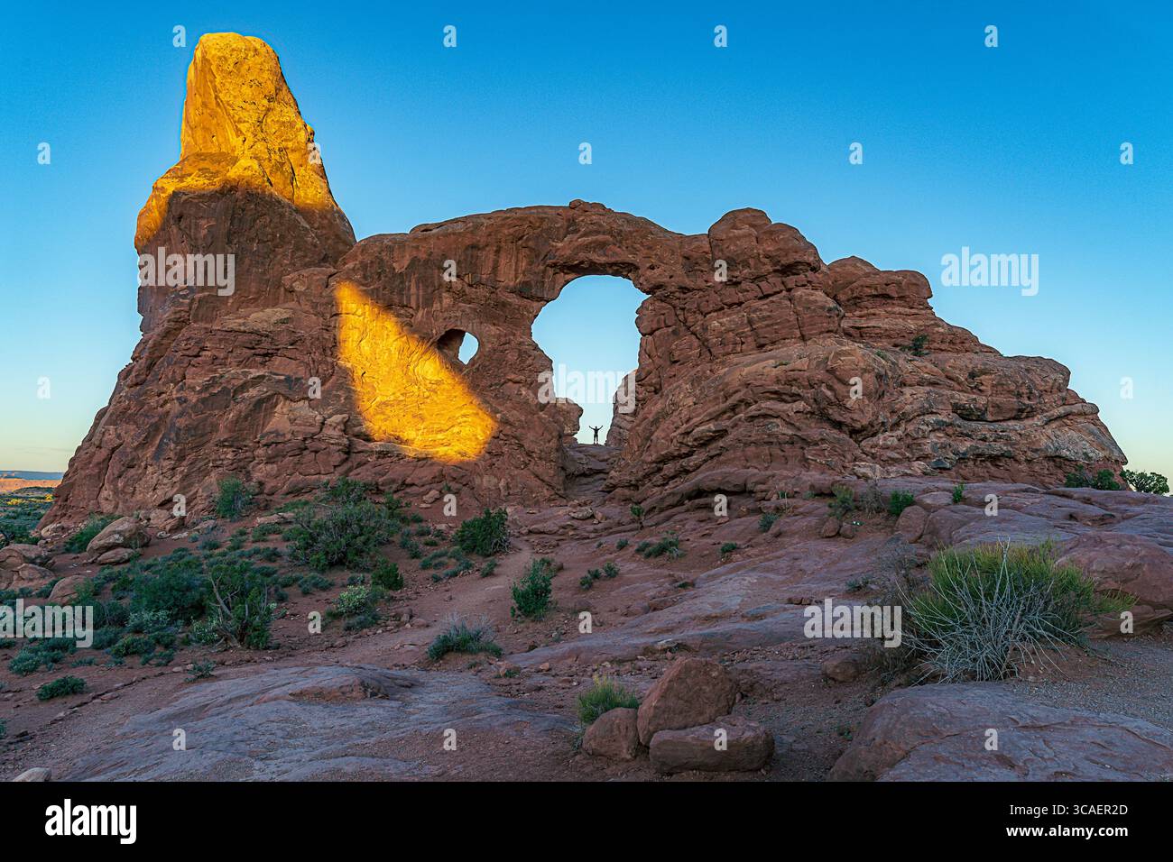 Un visitatore è sminuito dal Turret Arch nel Parco Nazionale degli Arches. Il parco è noto per le sue maestose formazioni di arenaria. Foto Stock