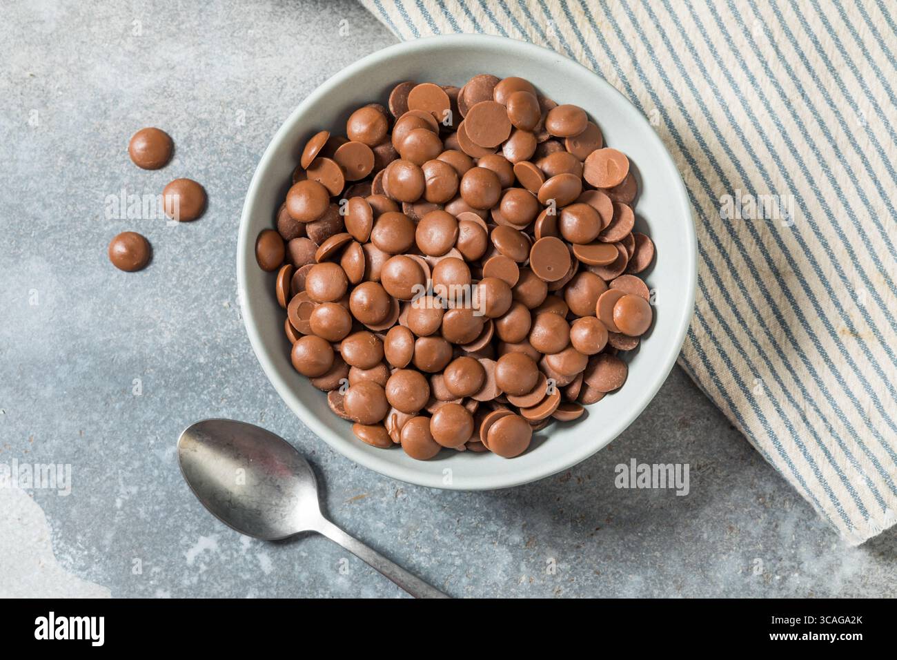 Scaglie di cioccolato al latte crudo biologico da cuocere in una ciotola Foto Stock