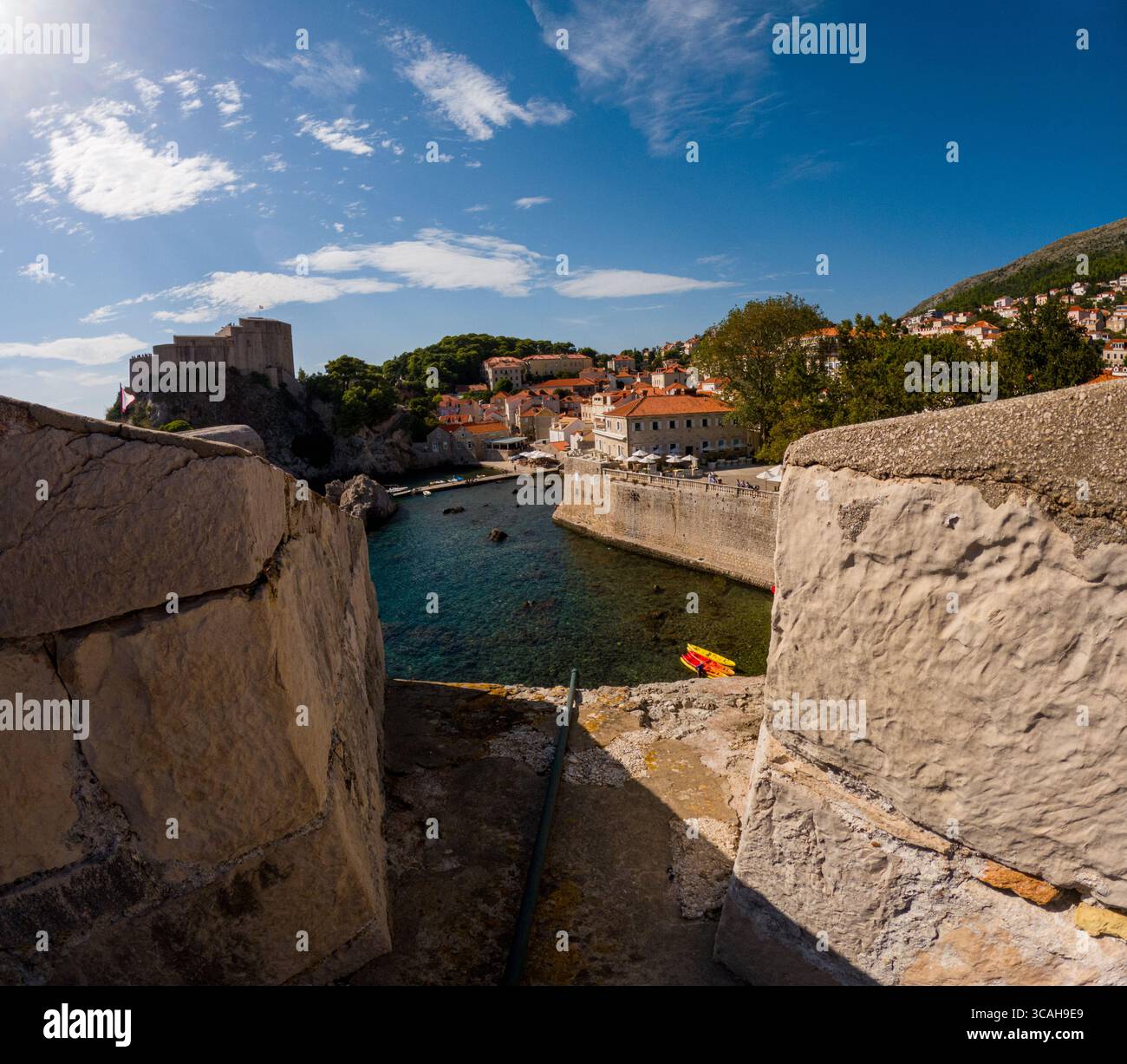 Dubrovnik, Croazia - 14 settembre 2023: Una vista dalle mura della città che si affaccia su un piccolo porto con kayak, che mostra l'architettura storica della città Foto Stock