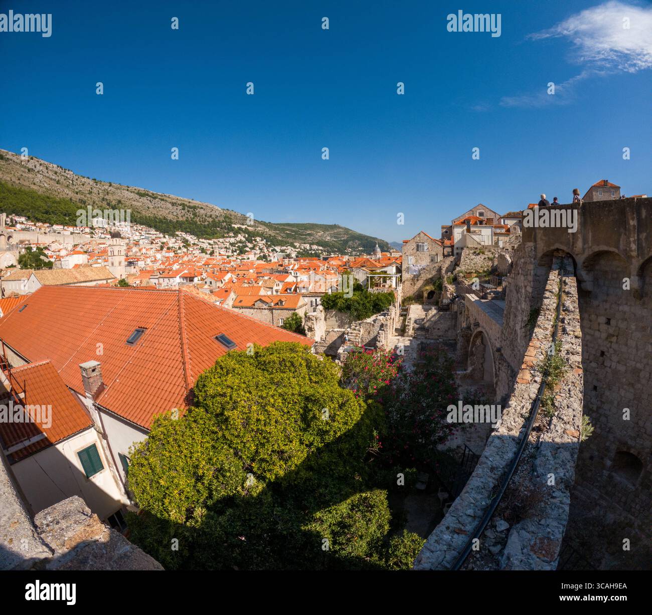 Dubrovnik, Croazia - 14 settembre 2023: I turisti esplorano le storiche mura della città, ammirando vedute panoramiche dei tetti di tegole rosse e dell'Adriat Foto Stock