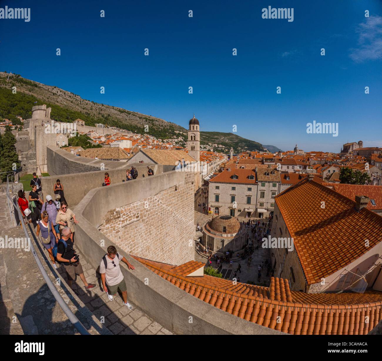 Dubrovnik, Croazia - 14 settembre 2023: I turisti esplorano le storiche mura della città, ammirando la vista sui tetti di tegole rosse. Foto Stock