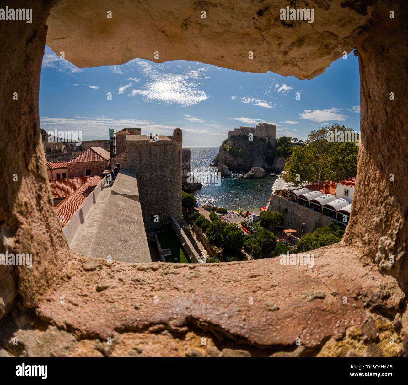 Dubrovnik, Croazia - 14 settembre 2023: I turisti esplorano le storiche mura della città, sbirciando attraverso un'apertura per vedere Fort Lovrijenac. Foto Stock