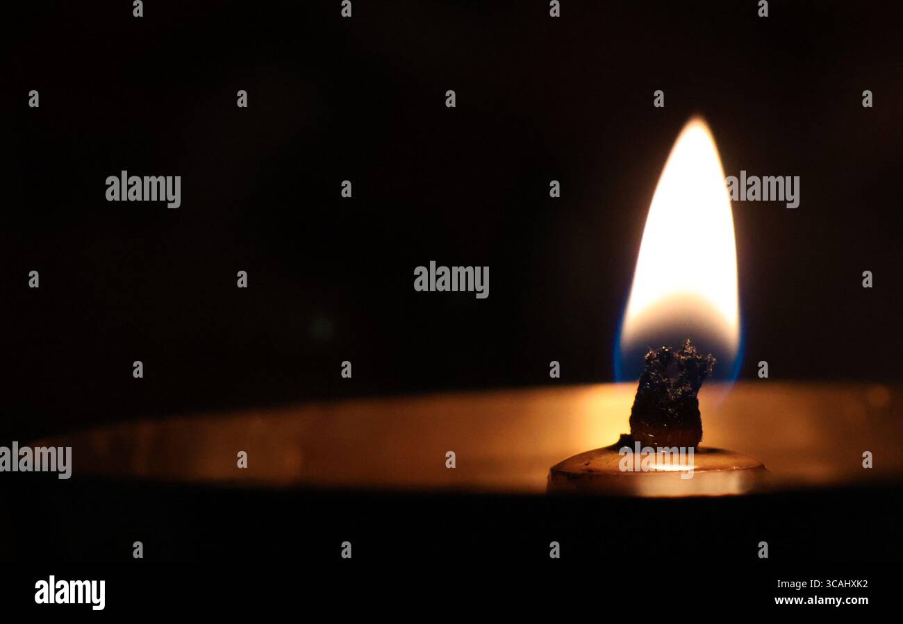 Una calda fiamma di candele che si illumina nel buio con una luce soffusa crea un'atmosfera tranquilla e rilassante con spazio per copiare. Sfondo minimo Foto Stock