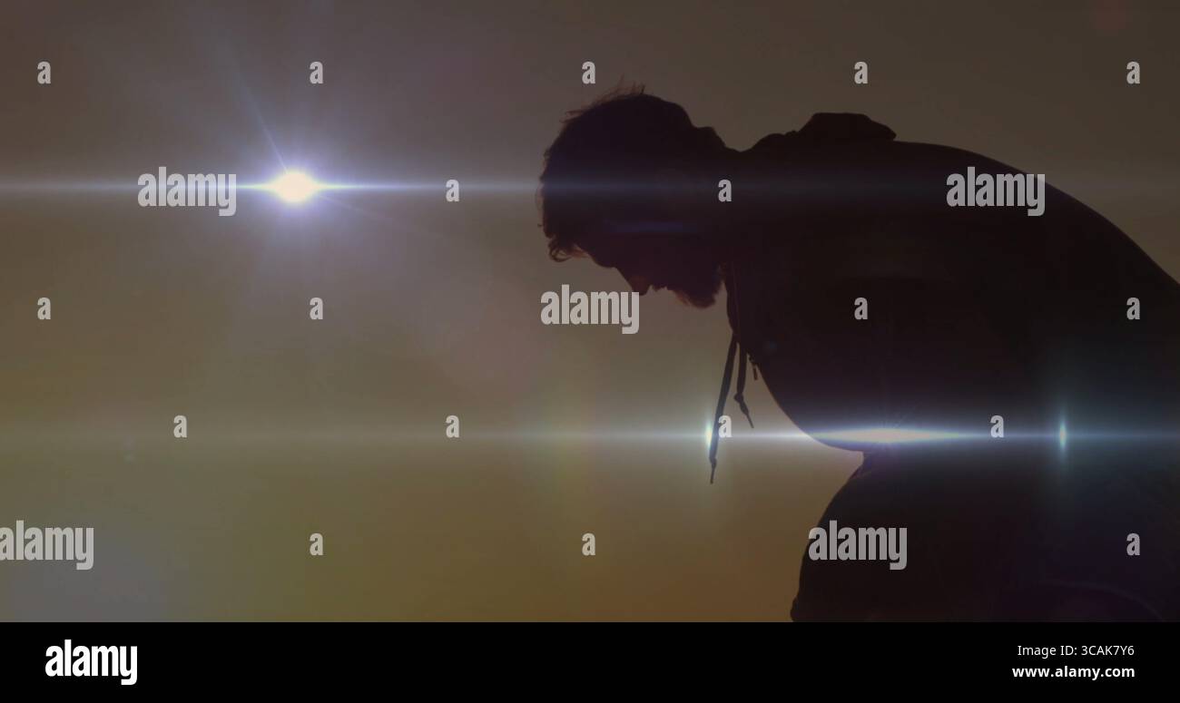 Silhouette da uomo inclinata in avanti con felpa con cappuccio al tramonto all'aperto, sole sospesi e spazio fotocopie Foto Stock