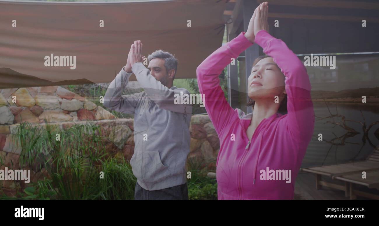 Pratica la coppia in abbigliamento sportivo mentre pratica yoga posa di preghiera sul ponte del giardino, con baldacchino e laghetto Foto Stock