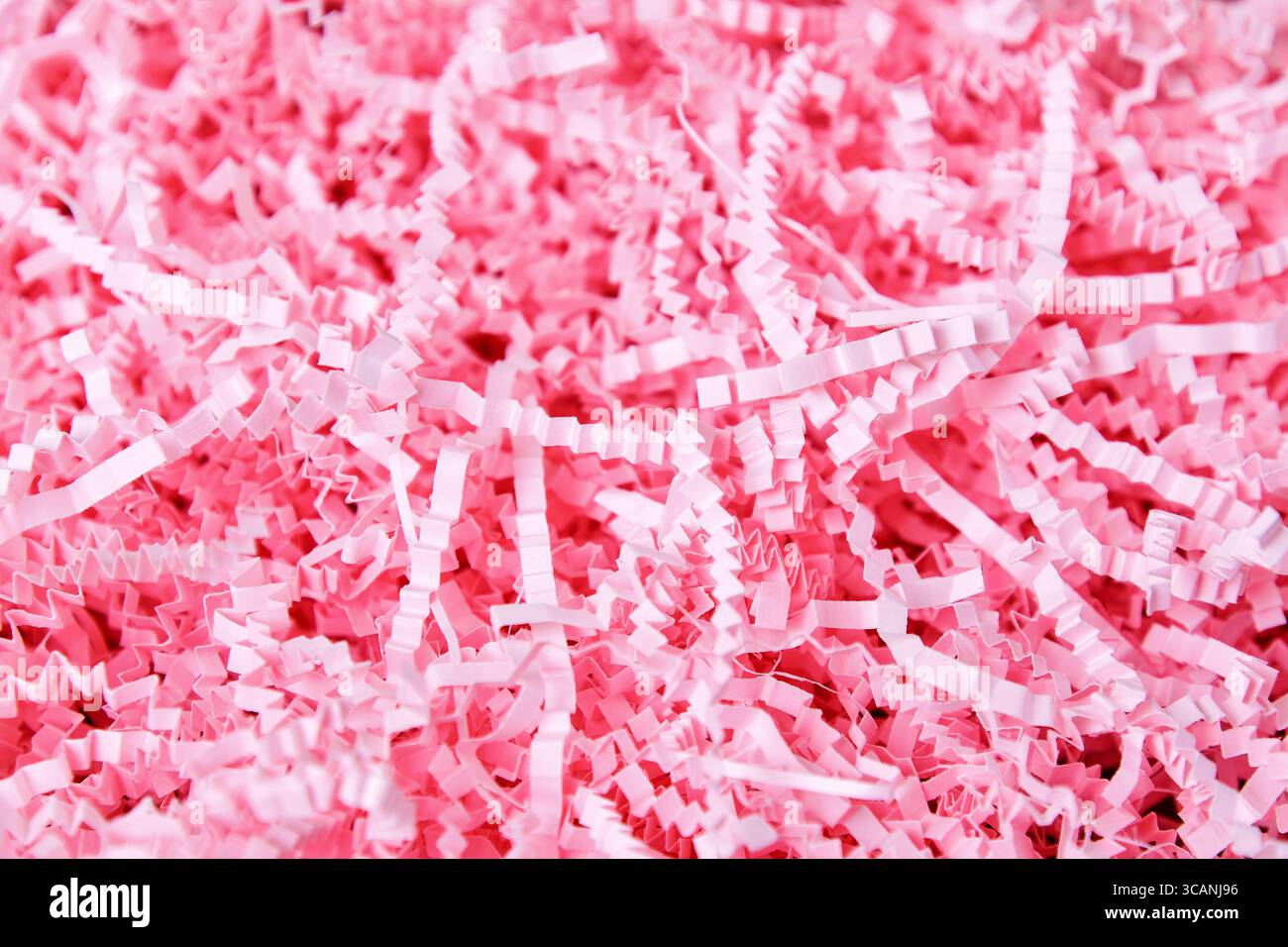 Foto ravvicinata di carta grattugiata rosa brillante, spesso utilizzata come riempitivo per cestelli regalo o materiale di imballaggio Foto Stock