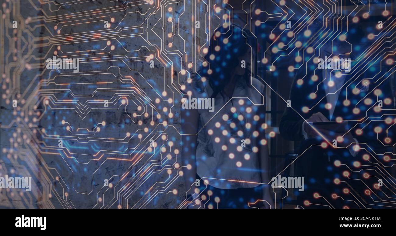 Colleghi che indossano abiti da lavoro che discutono della tecnologia in ufficio, con tablet e sovrapposizione del circuito Foto Stock