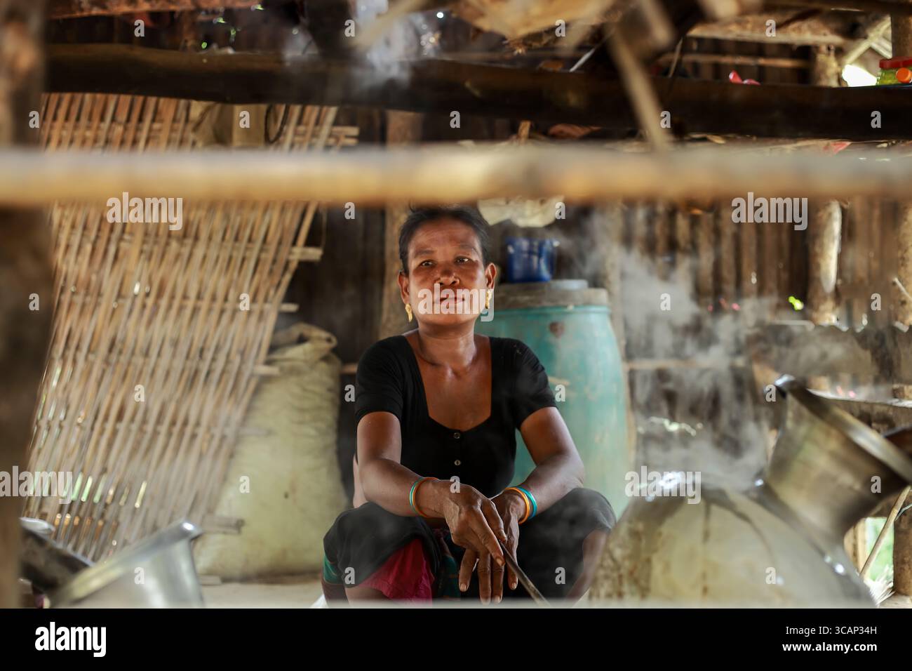 Mirsharai, Bangladesh - 21 ottobre 2019: Veduta di una donna tra vasi di vapore e metallo, il suo sguardo fisso sullo sfondo di una dimora rustica e strutturata in bambù. Foto Stock