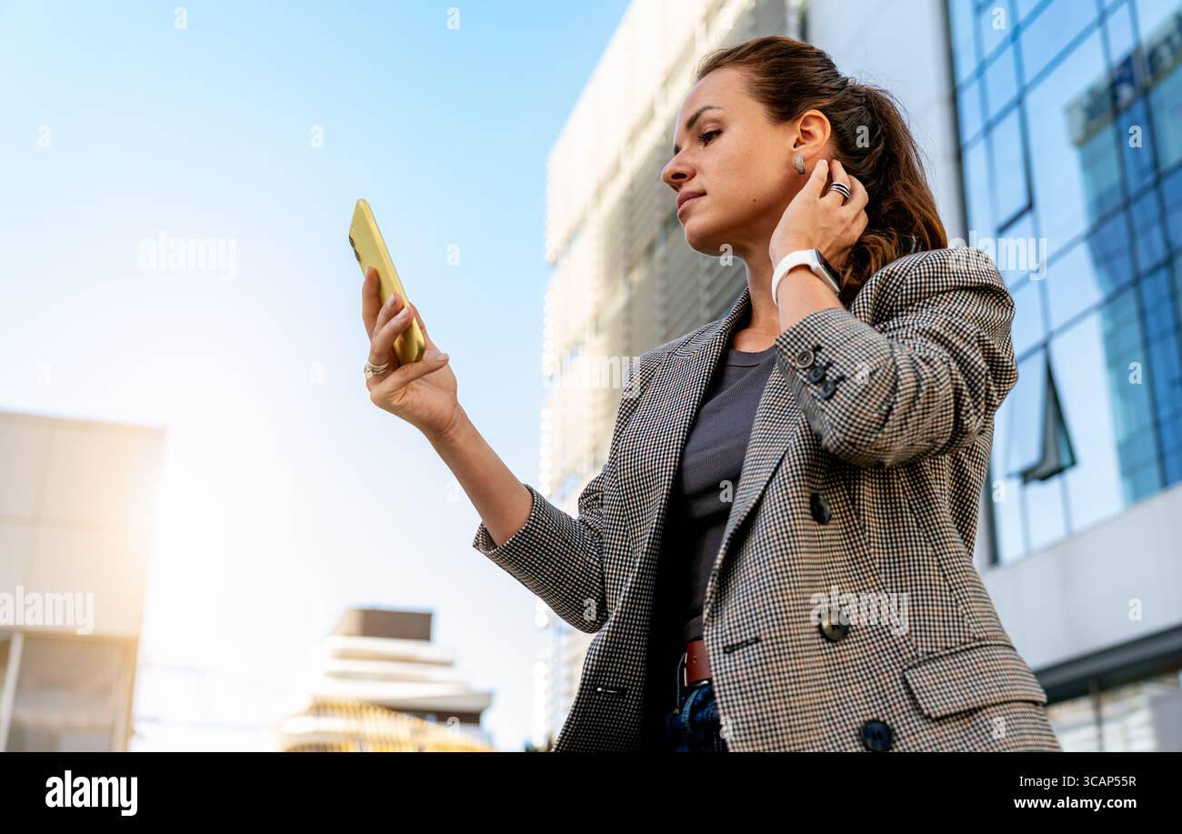 Donna moderna in città che guarda lo smartphone come uno specchio Foto Stock