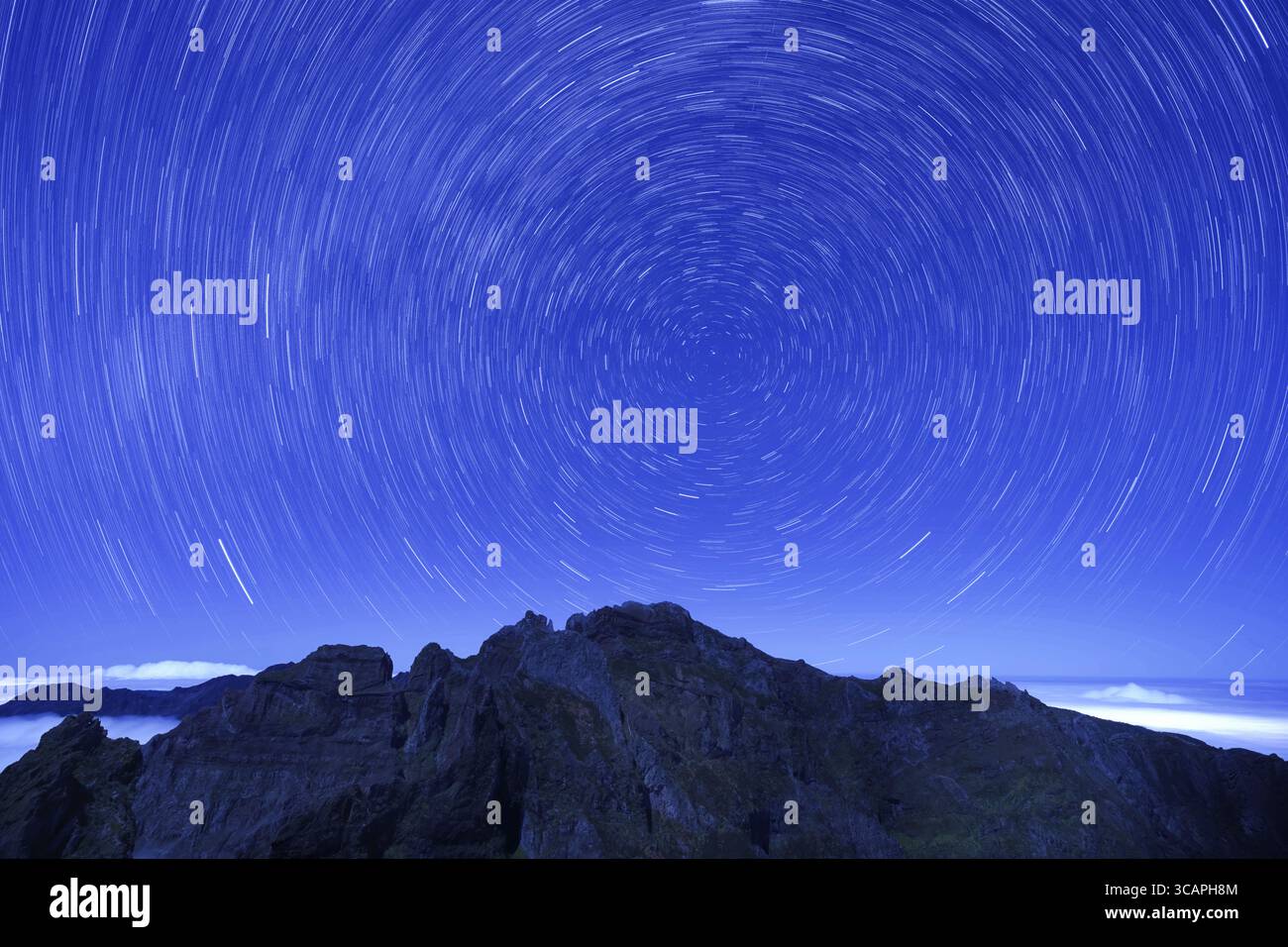 Vista di un'ipnotica danza celeste di stelle che oscillano sopra le frastagliate cime di montagna sotto un cielo blu profondo, creando un panorama mozzafiato, Funchal, Foto Stock