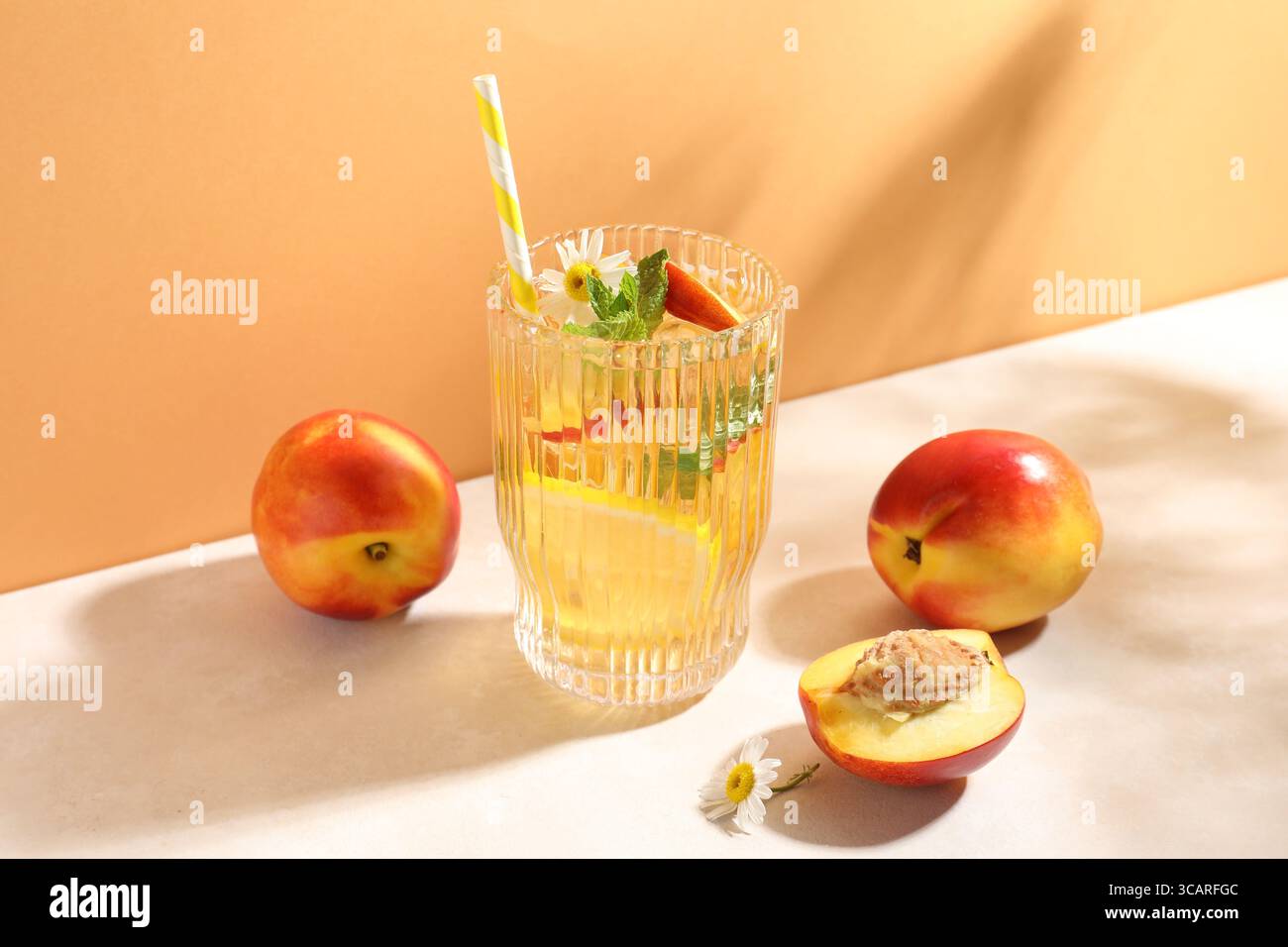 Gustoso tè freddo con pesche, limone, menta e fiori sul tavolo bianco Foto Stock