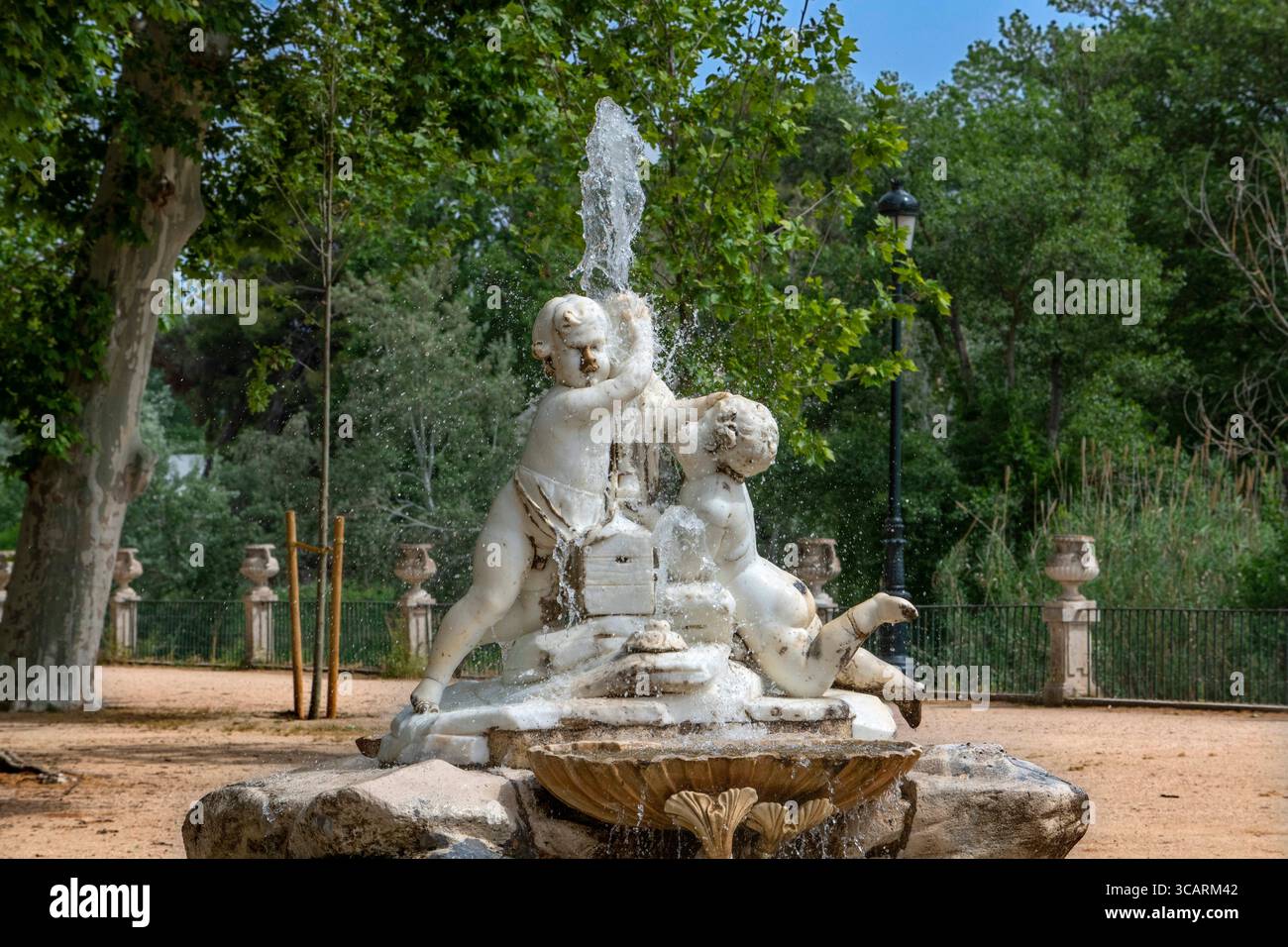 22 maggio 2022, Madrid, Spagna: Giardino dell'isola nei Giardini reali spagnoli, giardino del Parterre, Aranjuez, Spagna. Sala dei monarchi cattolici. Fontana della Boticaria all'inizio del Paseo de los Reyes CatÃ³licos. Nel 1777, sotto il regno di Carlo III, fu costruita una diga sul Tago lunga oltre 300 metri, sormontata da una ringhiera di ferro tra i piedistalli con vasi. Questo ha creato un ampio spazio che è stato trasformato in una passeggiata con la piantagione di diverse file di banani. All'inizio della passeggiata, entrando nel giardino attraverso il ponte orientale, la fontana del Boticaro Foto Stock
