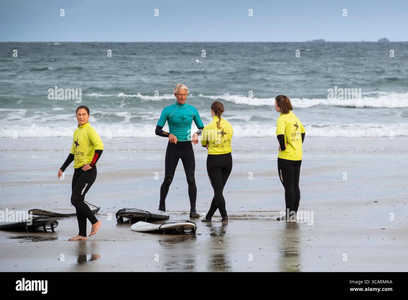 Un istruttore di surf della Escape Surfing School tiene una lezione di surf con un gruppo di studentesse a Towan Beach a Newquay in Cornovaglia nel Regno Unito. Foto Stock