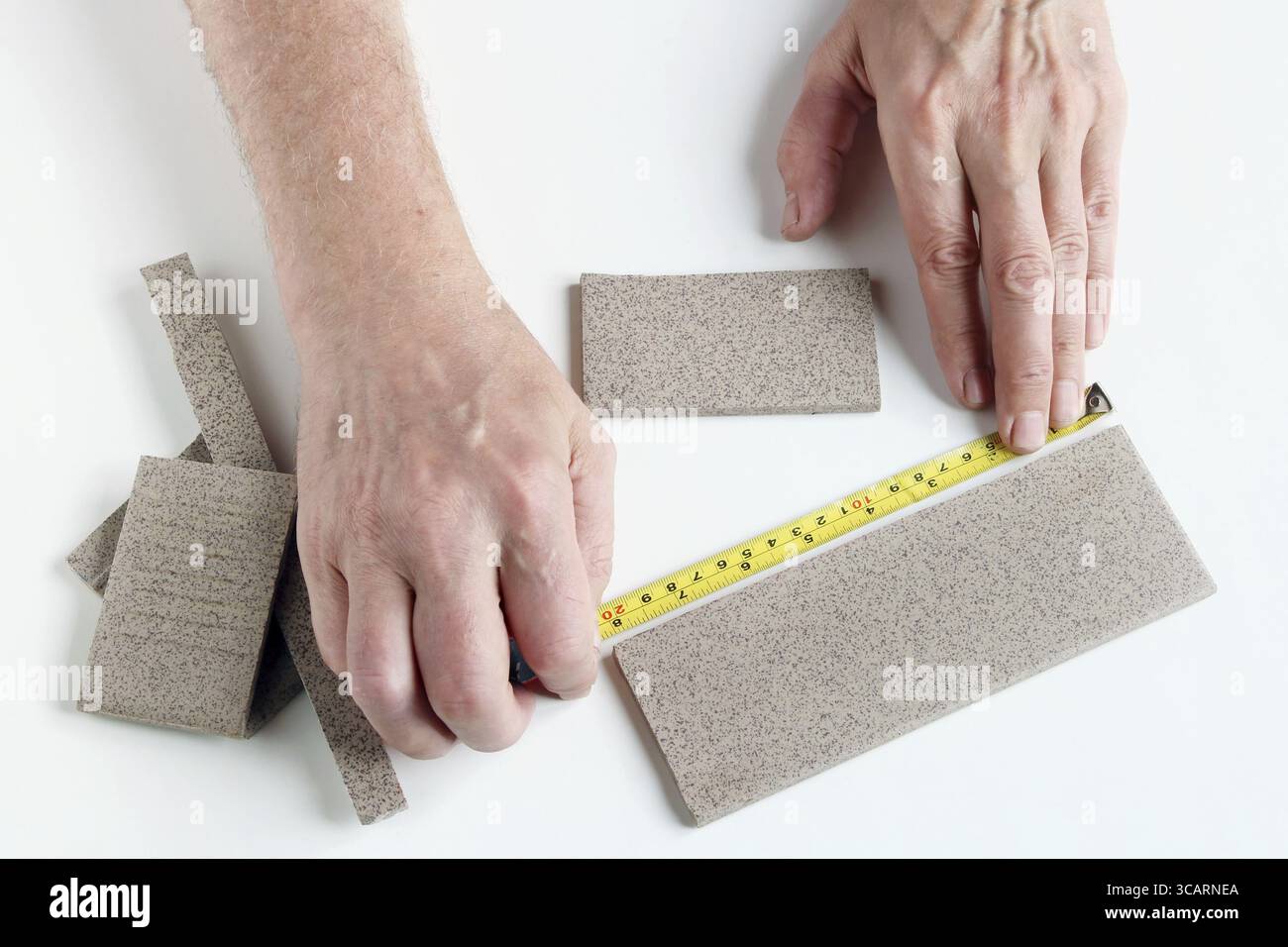 Il vecchio maestro misura la dimensione lineare delle stoviglie piastrelle sul tavolo bianco Foto Stock