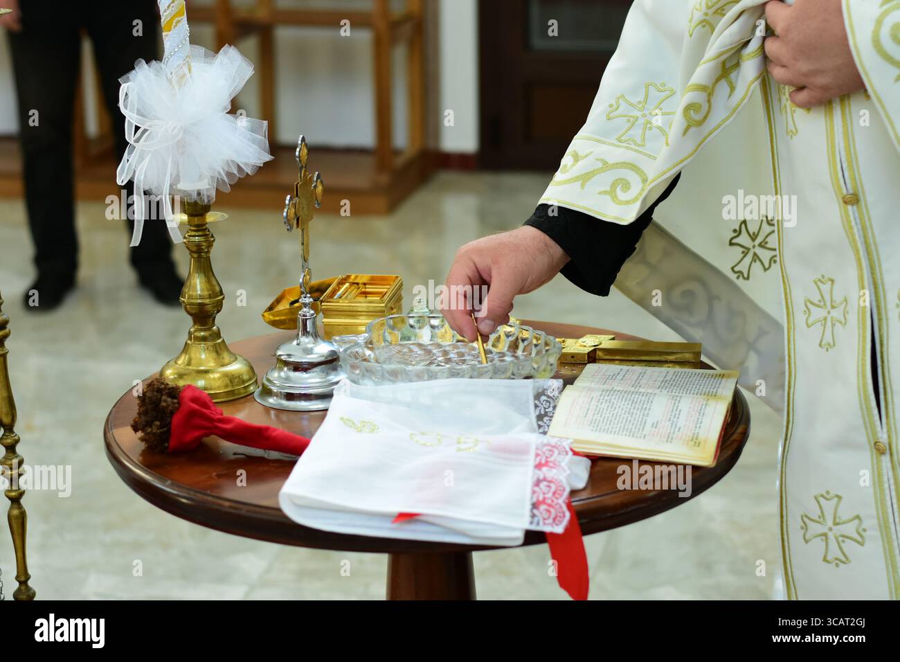 Sacerdote che benedice l'acqua Santa per la cerimonia del battesimo in chiesa Foto Stock