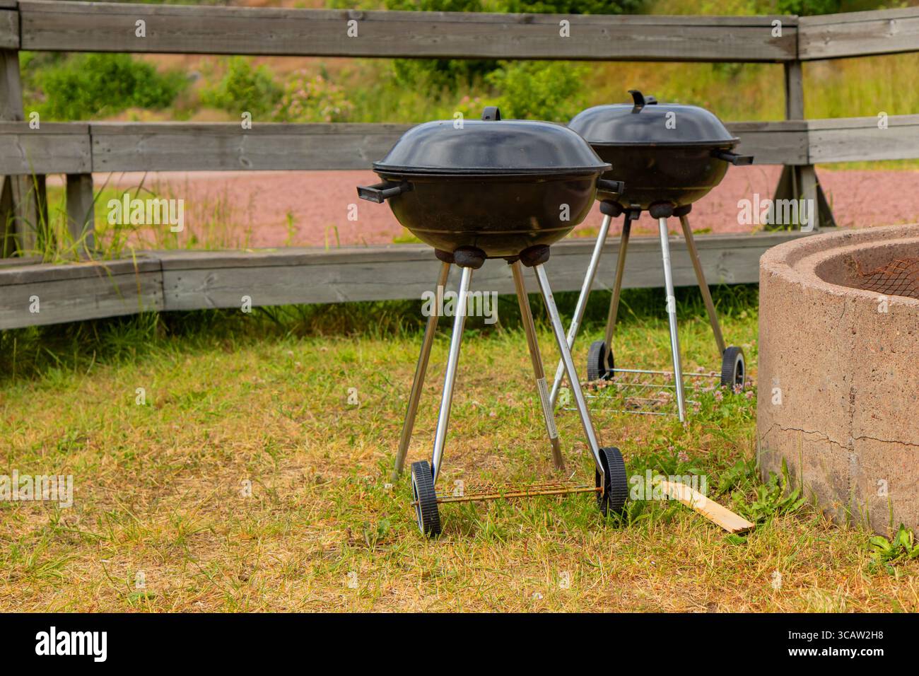 Classico bollitore per barbecue all'aperto in natura, rotondo e nero con coperchio a cupola, perfetto per grigliare al carbone durante picnic, gite in campeggio o backyar Foto Stock