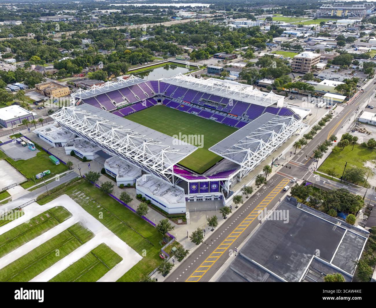 Orlando, Stati Uniti - 21 luglio 2025: Vista aerea dello Stadio Exploria inondato dalla luce del sole, i suoi posti a sedere viola si distinguono contro il lussureggiante campo verde, circondato dalle strade della città. Foto Stock