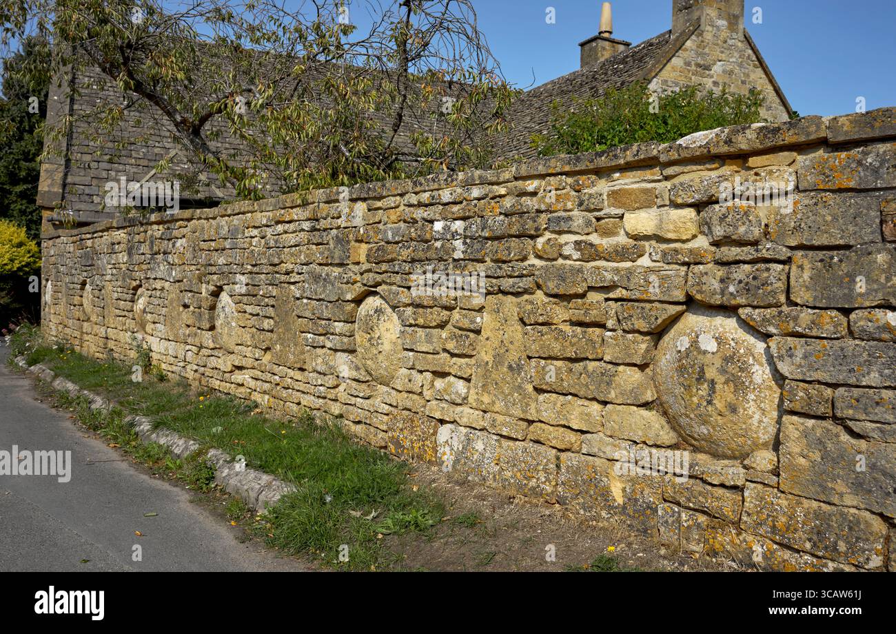Inusuale e decorativa parete in pietra Cotswold con inserti circolari in pietre a sella. Villaggio di Snowshill, Cotswolds, Gloucestershire, Inghilterra, Regno Unito Foto Stock