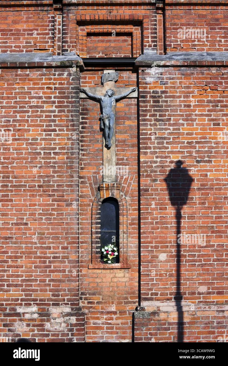 Il bronzo antico la crocifissione di Cristo si blocca su un mattone rosso sfondo a parete. Giornata di sole Foto Stock